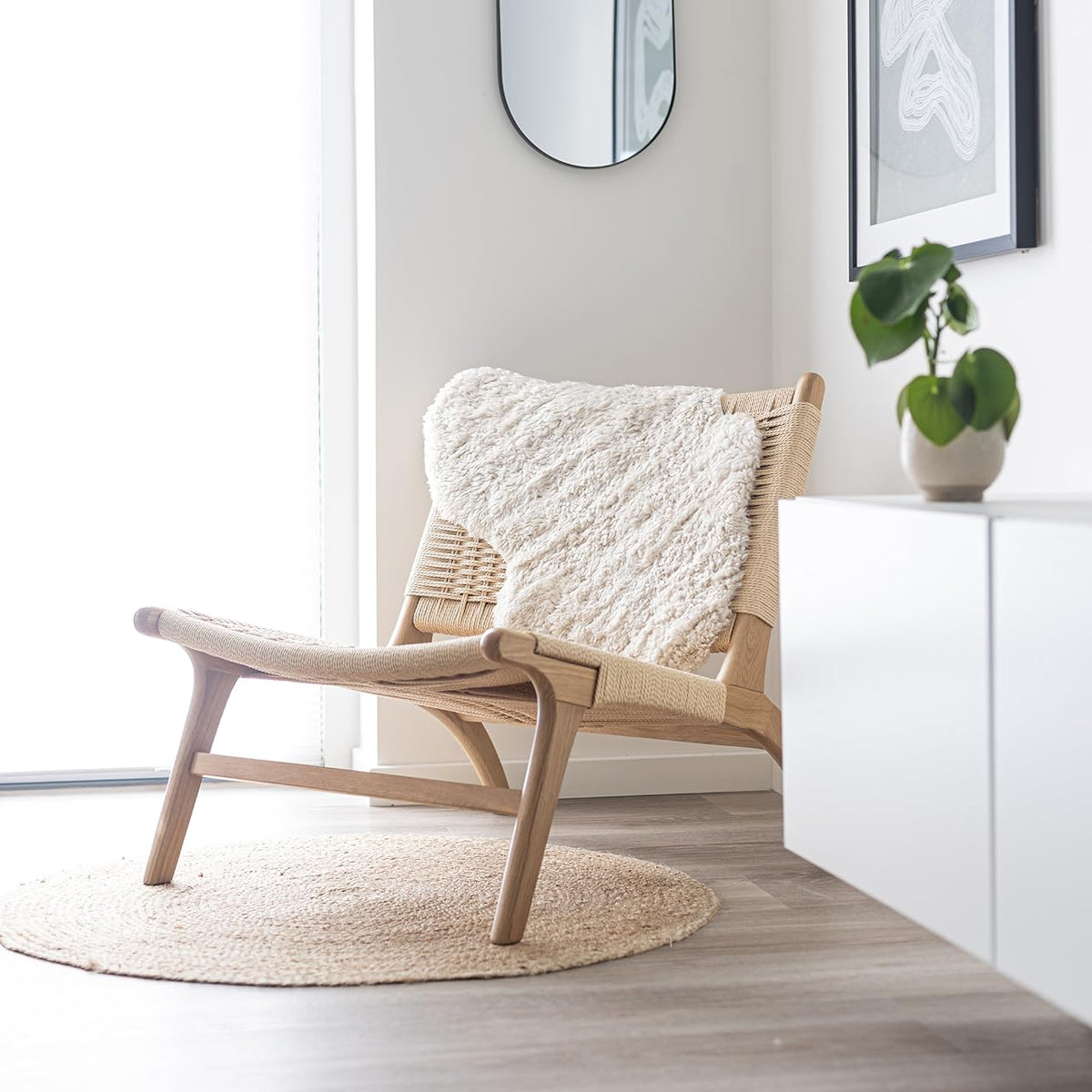 Crèmekleurige lamsvacht over een Scandinavische fauteuil bij het raam